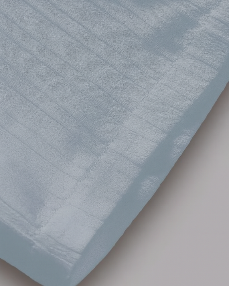 Bottom hem and fabric texture close-up of light blue pleated men's drawstring trousers