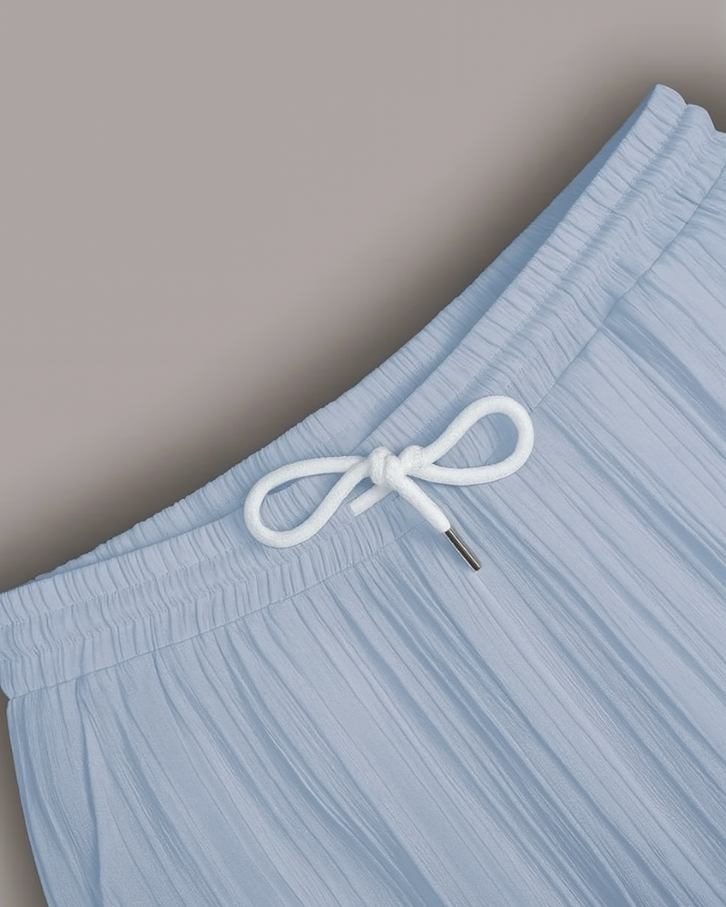Close-up of elastic waistband and white drawstring on light blue pleated trousers for men