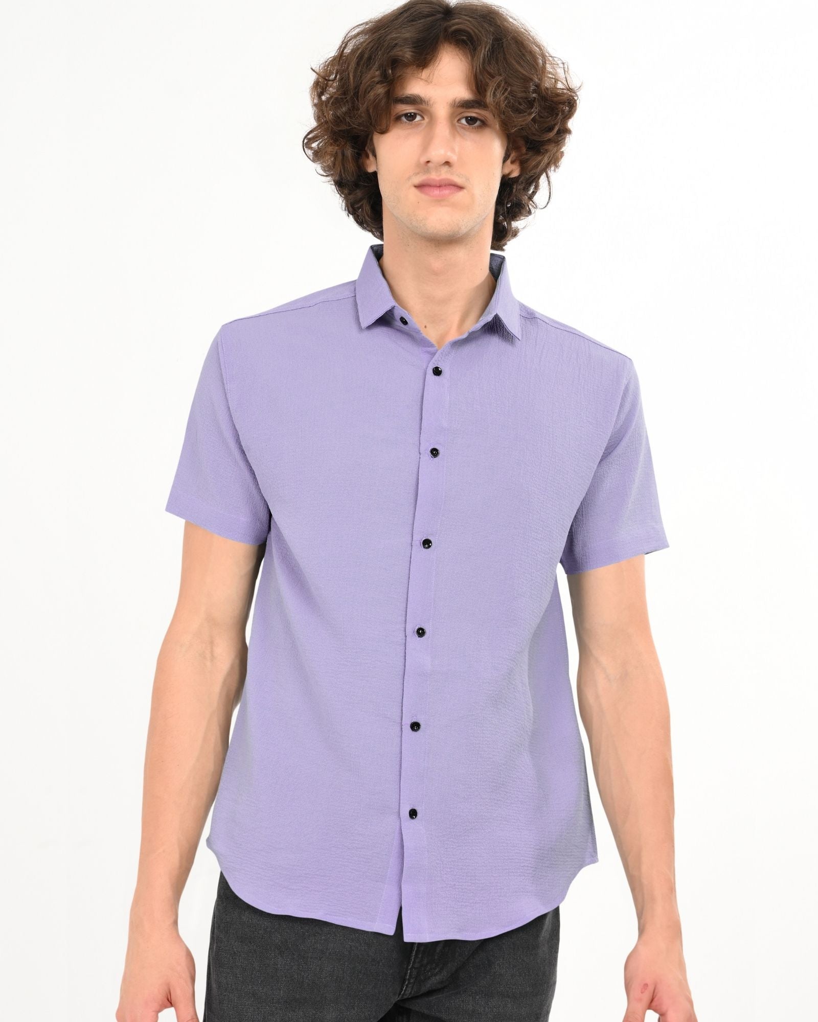 Front view of man wearing lavender short-sleeve textured button-up shirt paired with black jeans