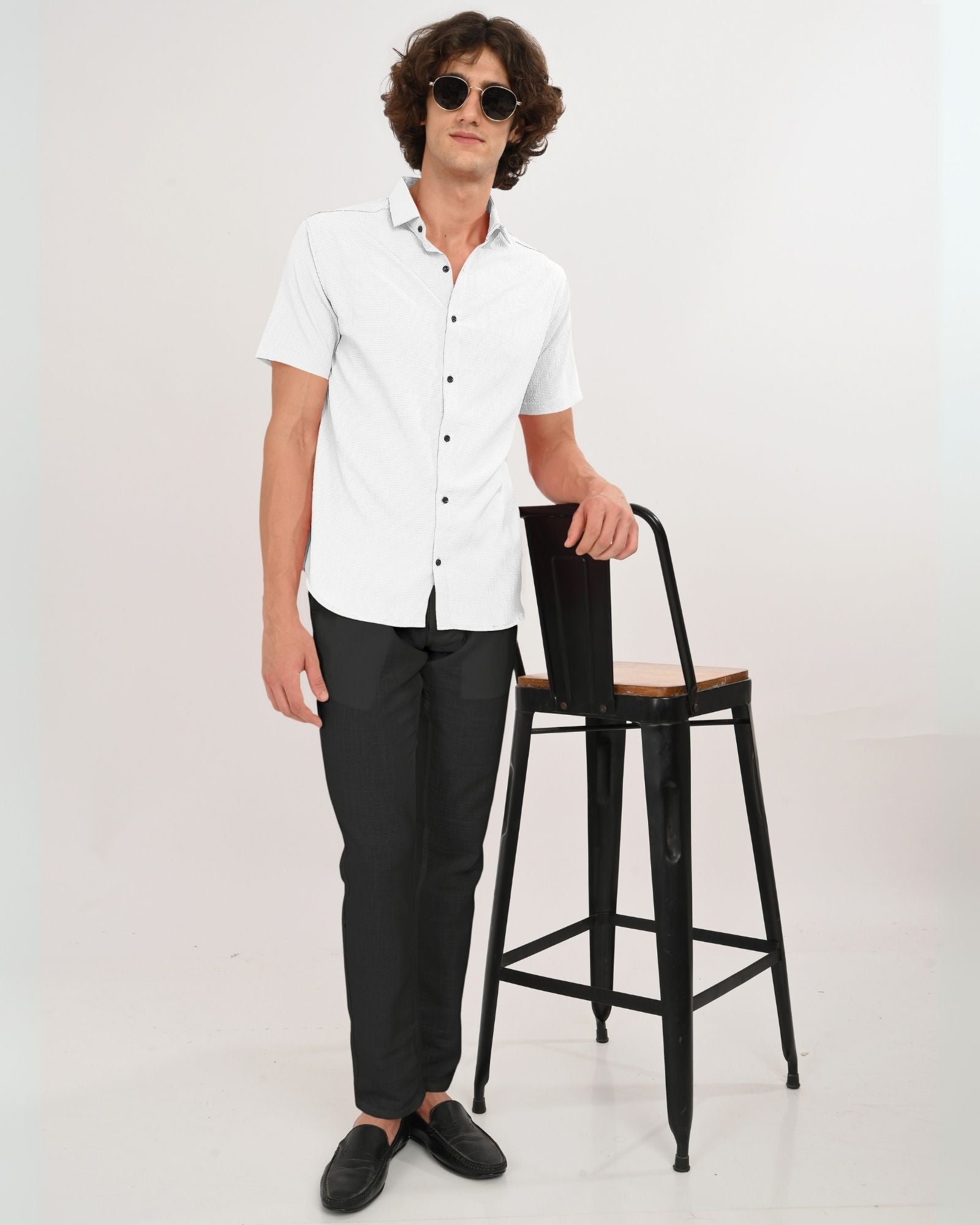 Full body shot of man in white short sleeve shirt paired with black trousers and loafers