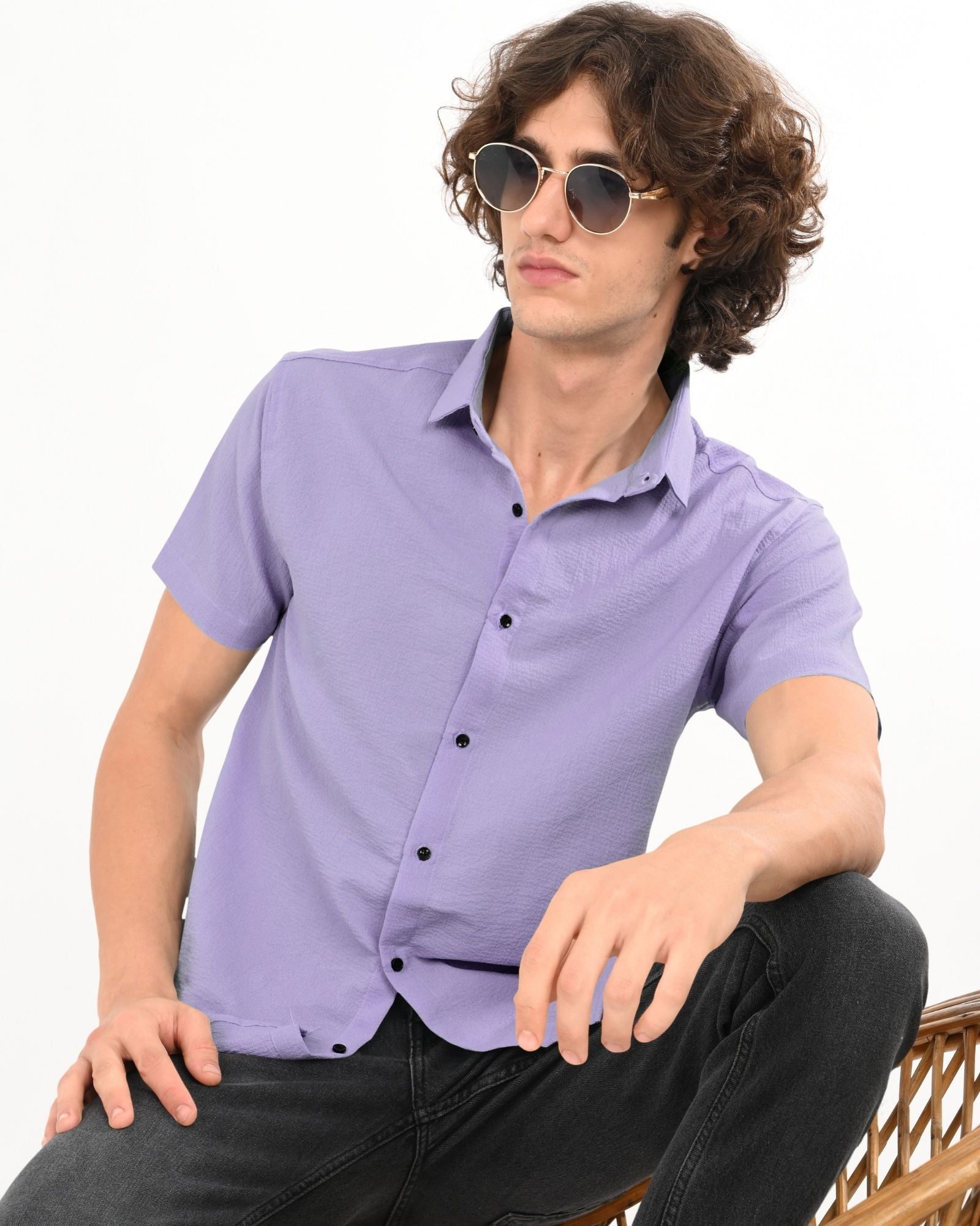 Man in sunglasses posing in lavender short-sleeve button-up shirt and black jeans