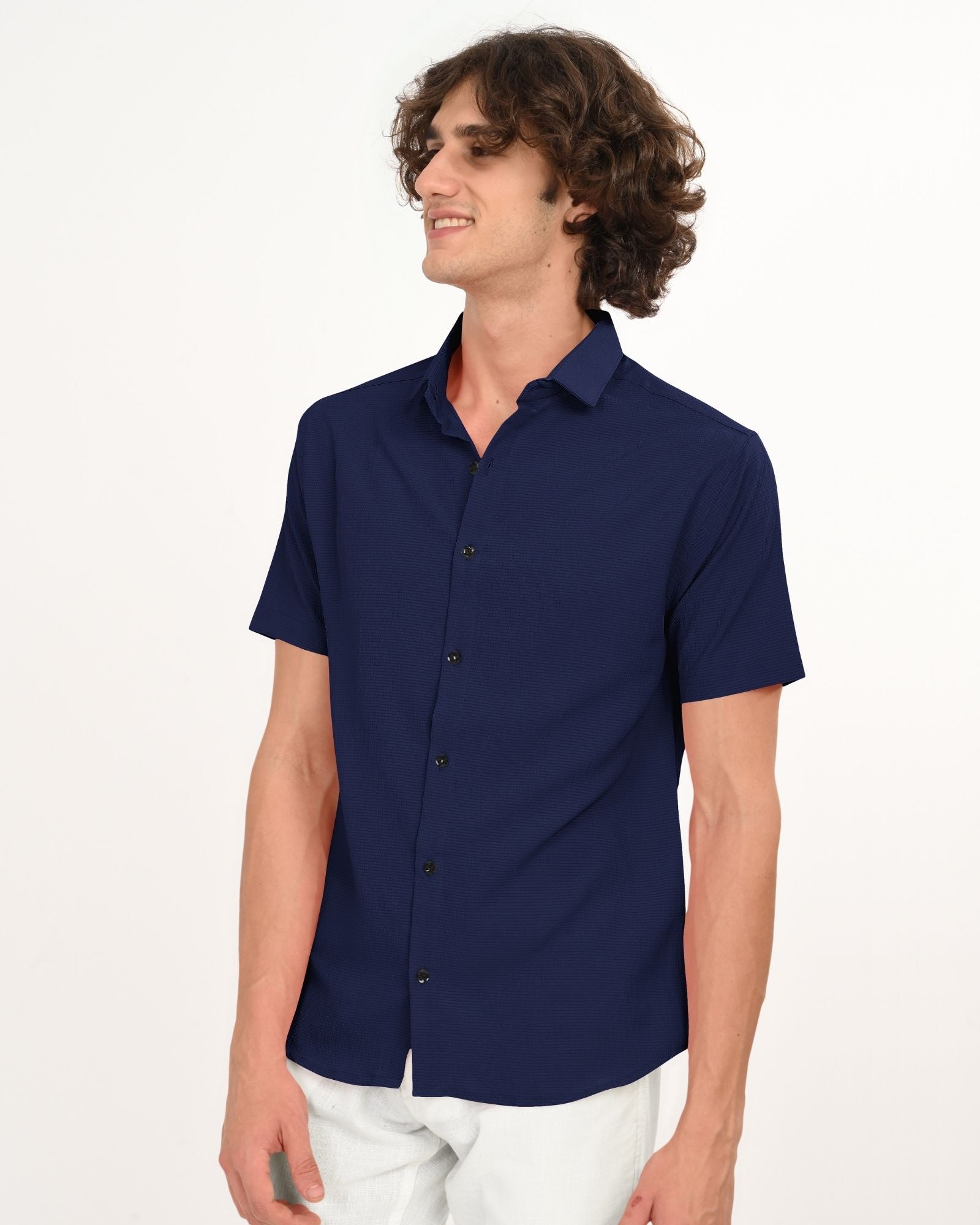 Man wearing navy textured short-sleeve button-up shirt, side view with white pants