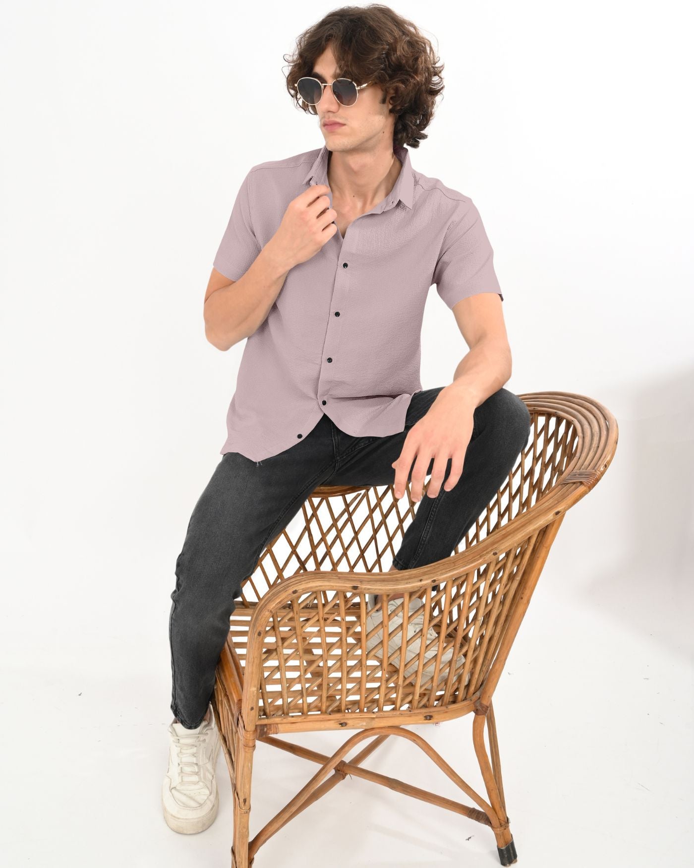 Model in dusty mauve crinkle shirt sitting on wicker chair