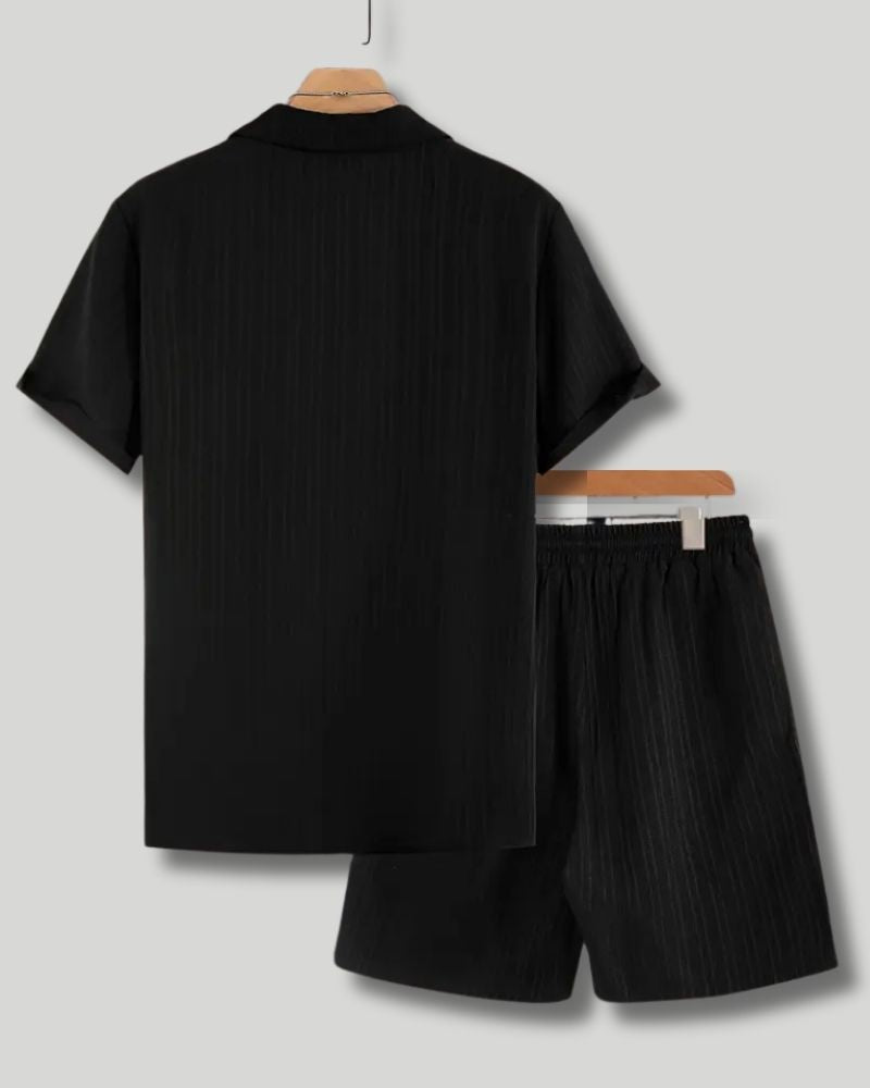 Black shirt and shorts set on hangers against a light gray background