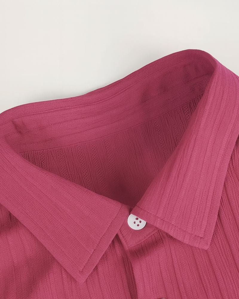 Close-up of a pink shirt collar with a button on a white background