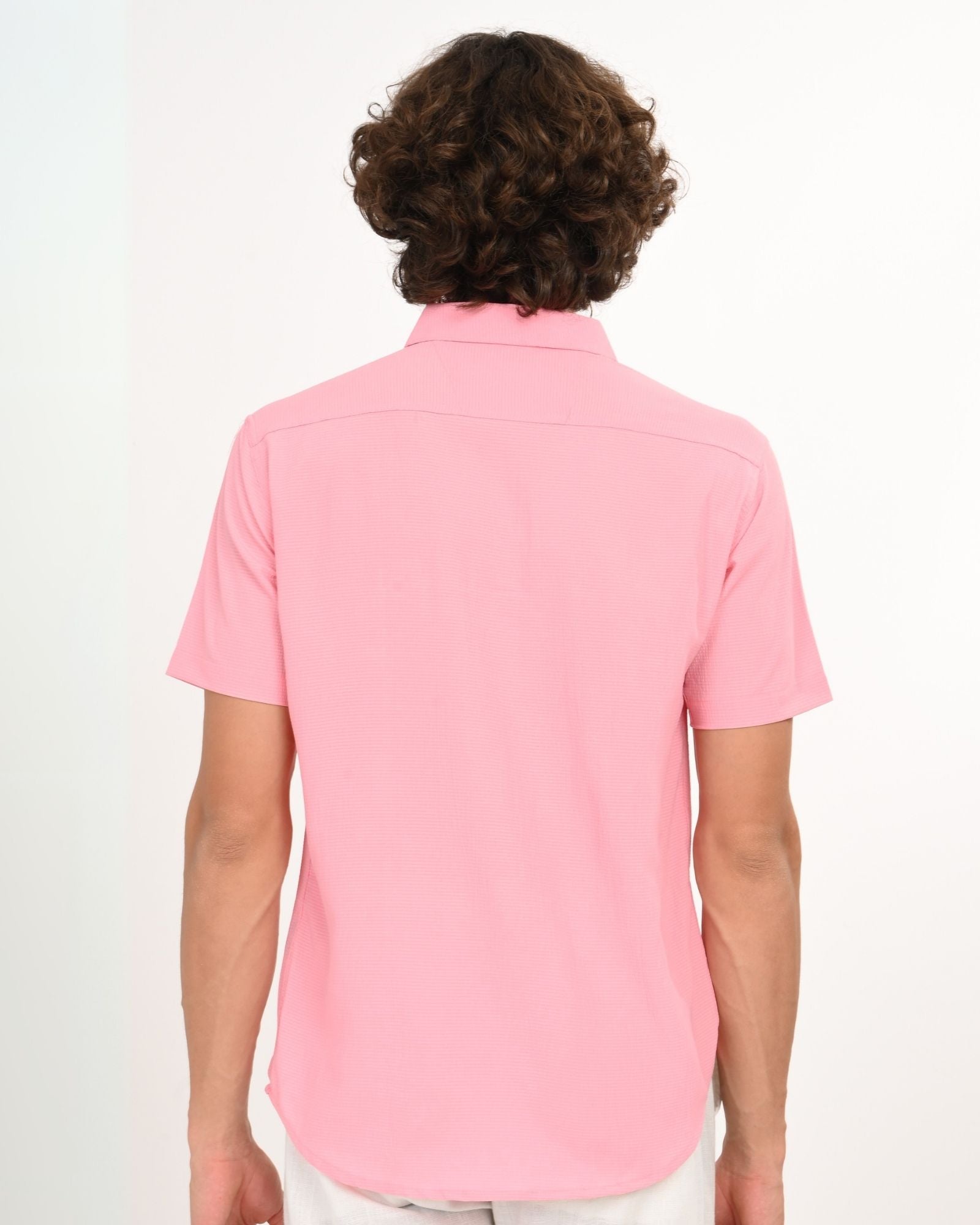 Back view of a light pink short sleeve shirt with curved hem worn by a man
