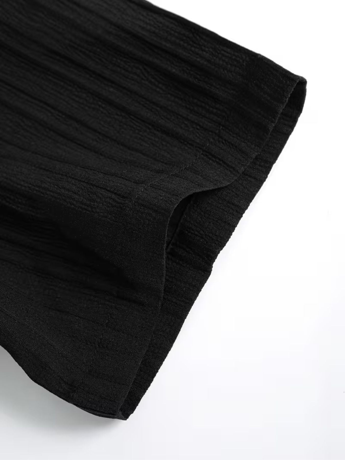 Close-up of black textured fabric showing soft crinkled finish and stitched short sleeve hem