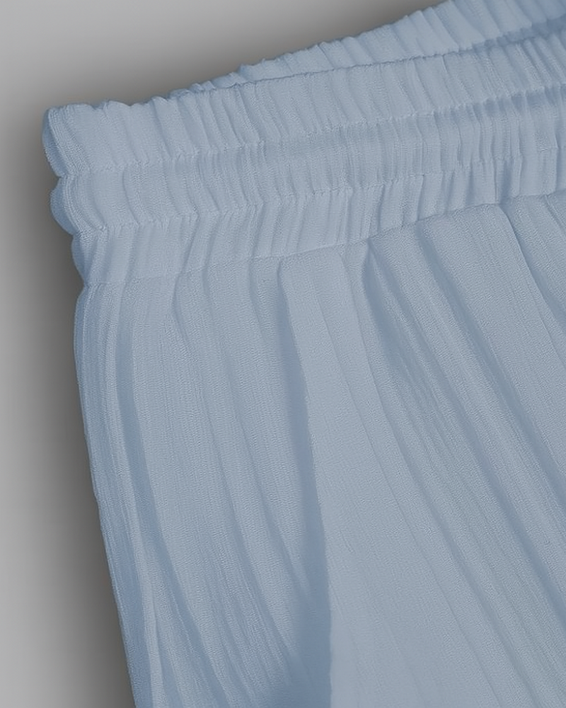Detail of gathered elastic waistband and pleated texture on light blue men’s trousers

