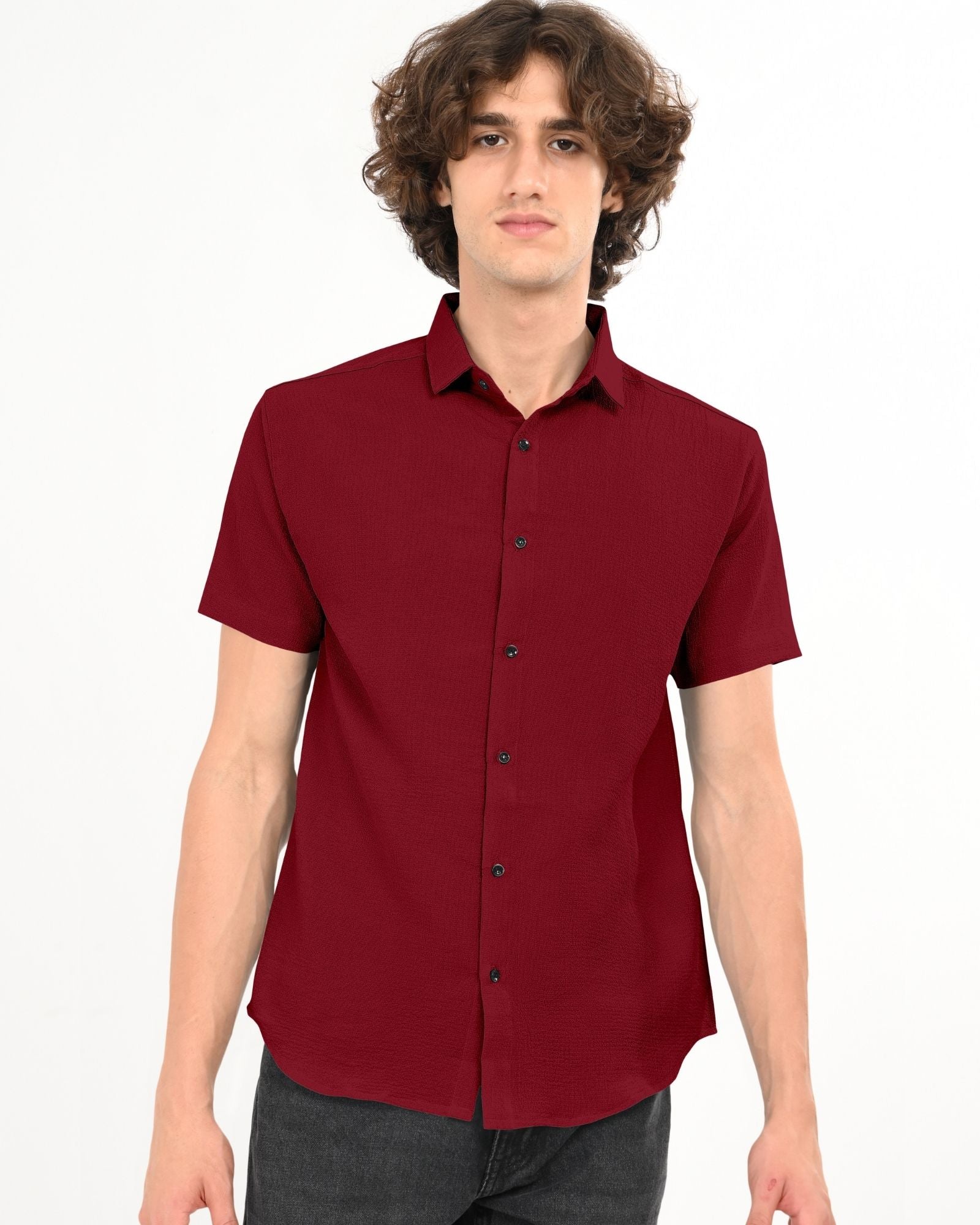 Front view of a man standing and wearing a crimson red short sleeve textured button-down shirt.