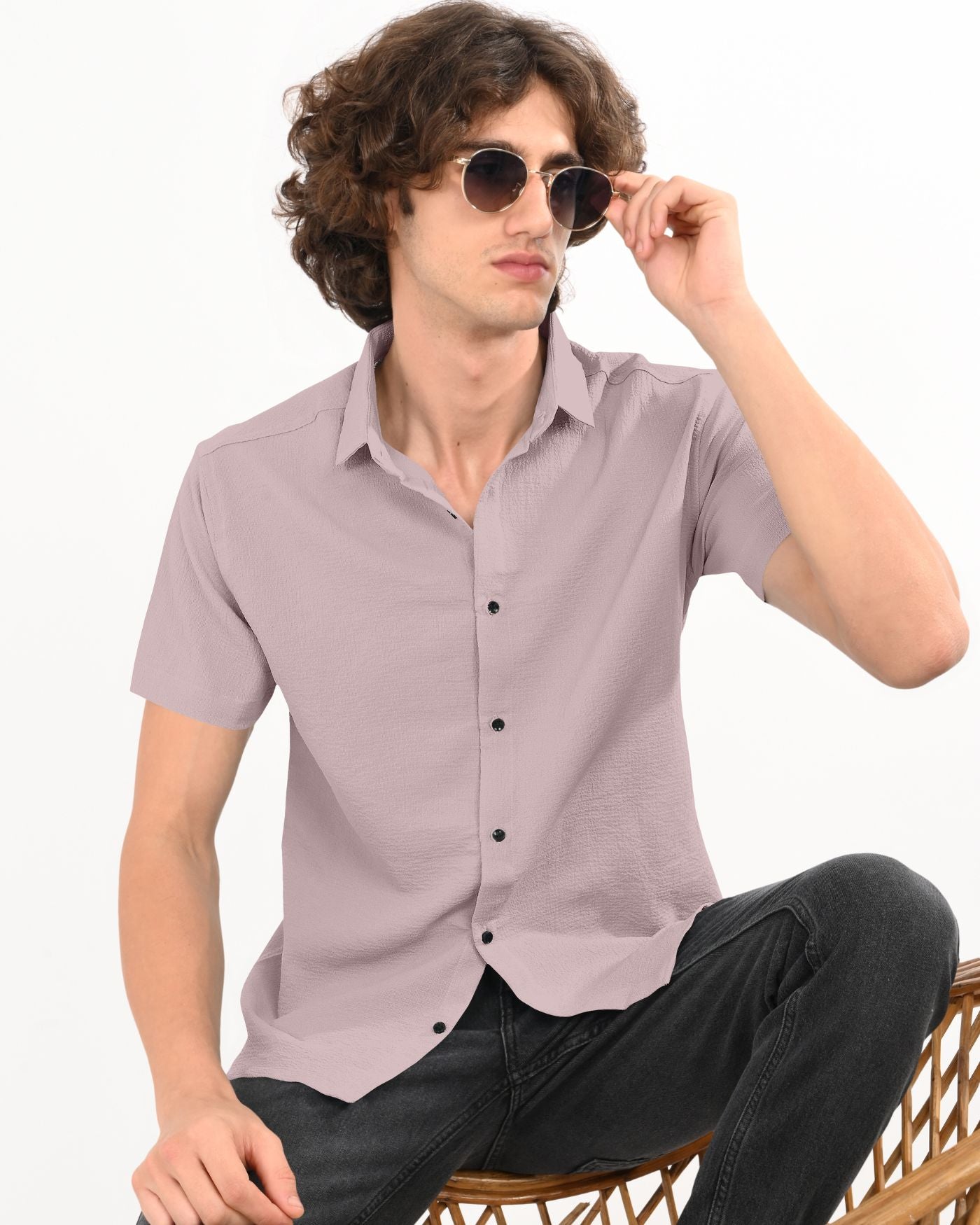 Man wearing dusty mauve crinkle textured short sleeve shirt sitting on chair