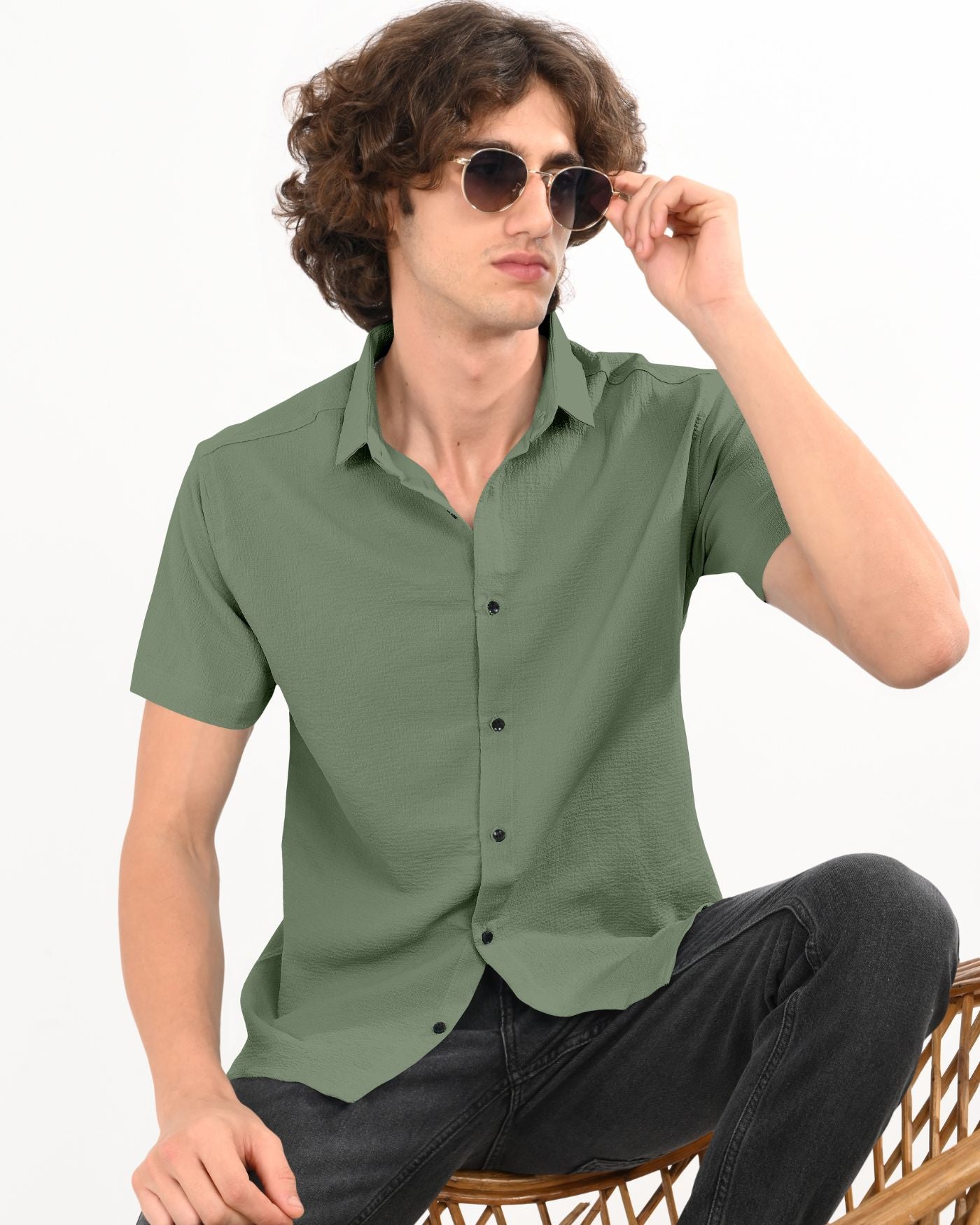 Men’s olive green short sleeve crinkle shirt with sunglasses sitting pose