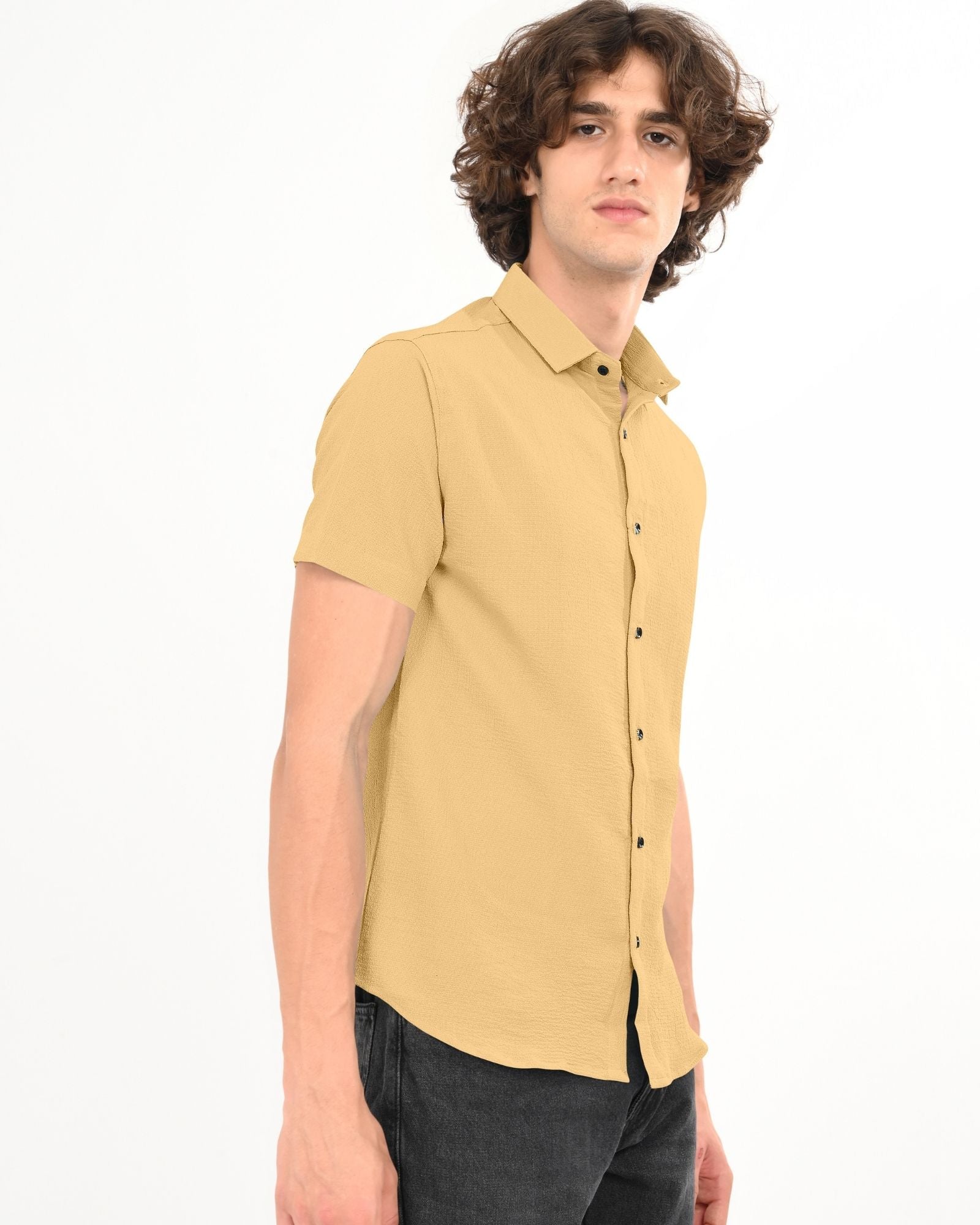 Side angle of man wearing beige textured short sleeve shirt with black buttons