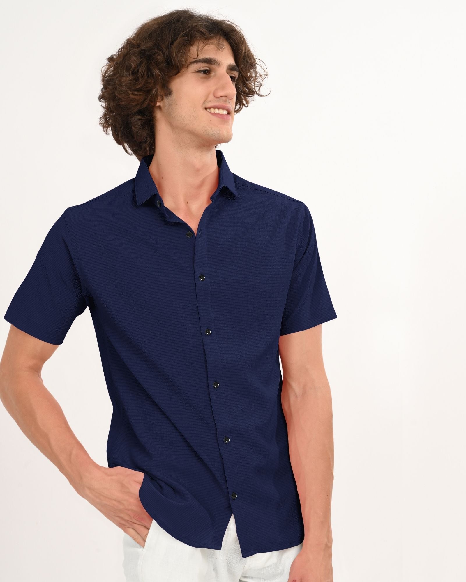Side angle of man wearing navy textured short-sleeve shirt with white pants