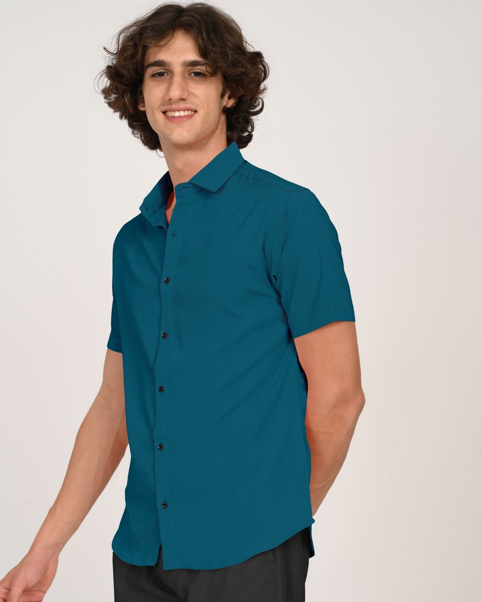 Side view of man smiling in teal short sleeve button-down shirt