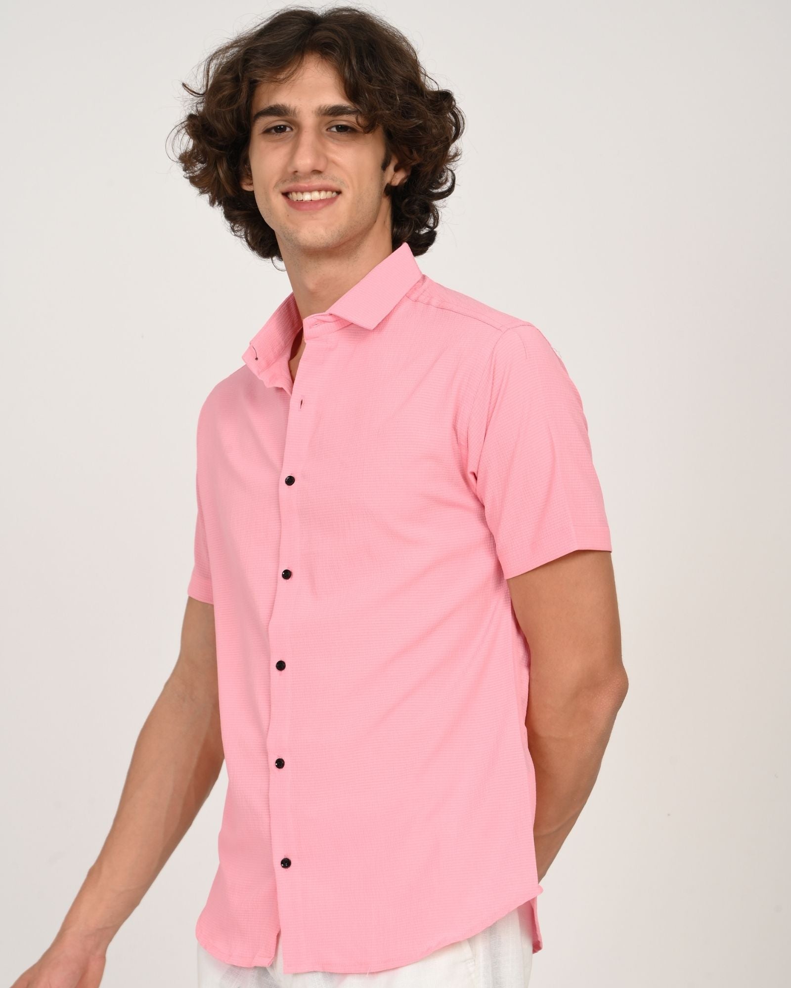 light pink short sleeve button-down shirt, side angle, smiling with hands behind back