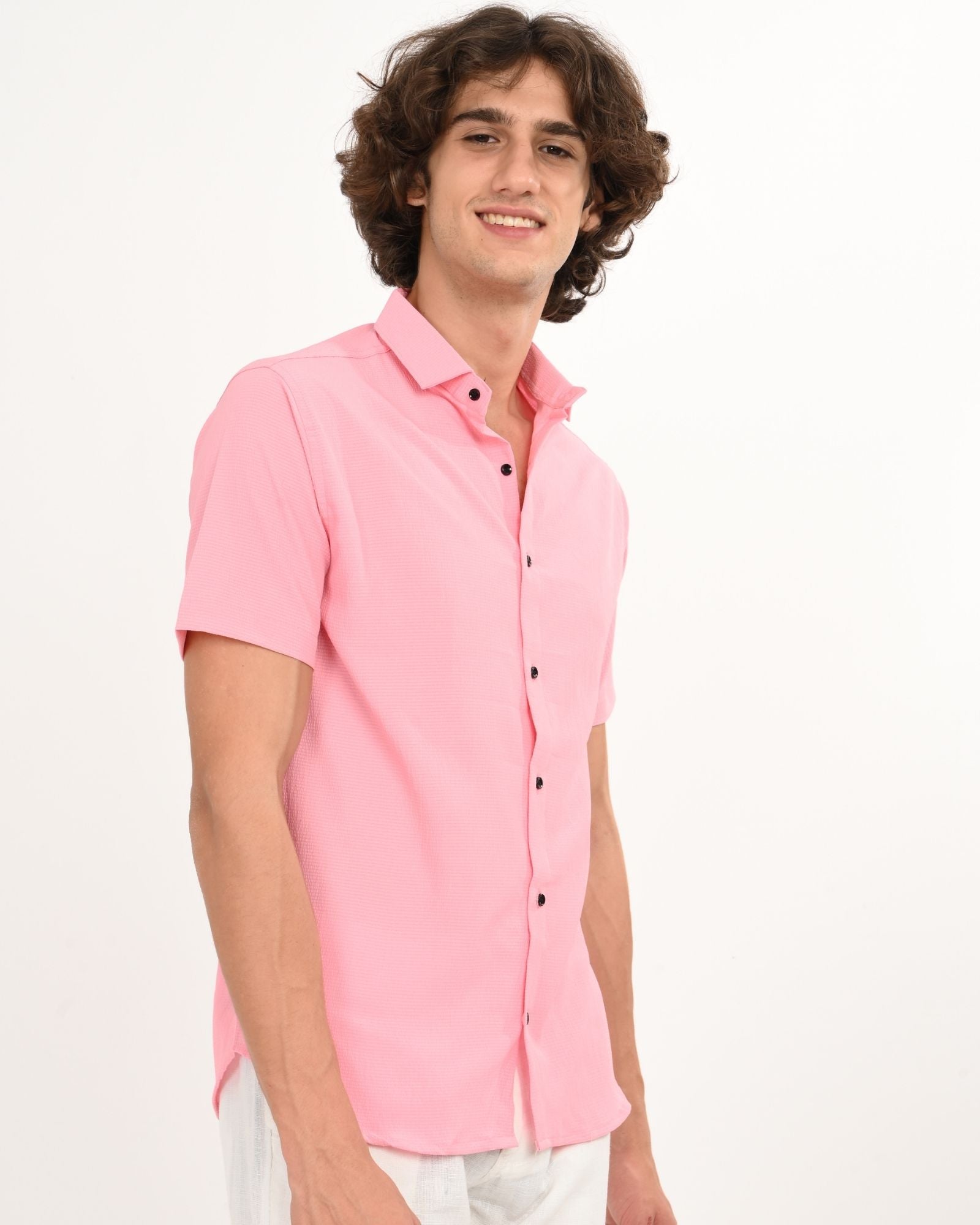 pink short sleeve button-down shirt with black buttons, slight side pose